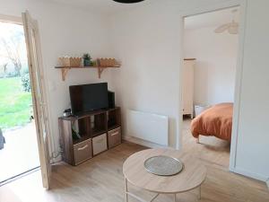 a room with a bed and a tv and a table at Maisonnette à la campagne in La Couyère