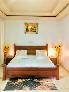 a bedroom with a large bed with two lamps and flowers at Gravity Villa Musanze in Ruhengeri