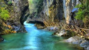 a wooden bridge over a river in a canyon at La Ribera in Arroyo Frio