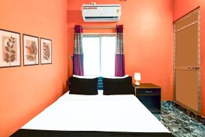 a bedroom with orange walls and a bed and a window at Hotel O by OYO ALO Hotel in Phulbāri