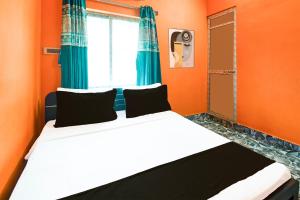a bedroom with a bed with orange walls and a window at Hotel O by OYO ALO Hotel in Phulbāri