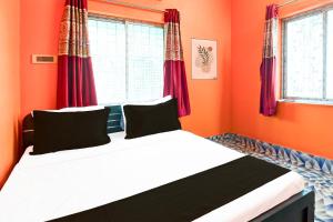 a bed in a room with orange walls and windows at Hotel O by OYO ALO Hotel in Phulbāri