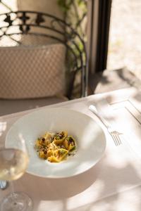a plate of food on a table with a glass of wine at Villa di Piazzano - Small Luxury Hotels of the World in Cortona
