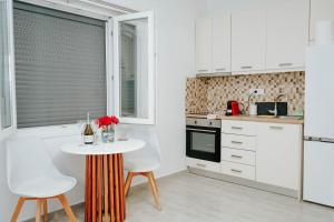 a kitchen with white cabinets and a table and chairs at LV Luxury Apartment in Parga