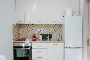 a kitchen with white cabinets and a sink at LV Luxury Apartment in Parga +27 photos