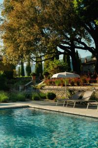 a swimming pool with two lounge chairs and an umbrella at Villa di Piazzano - Small Luxury Hotels of the World in Cortona