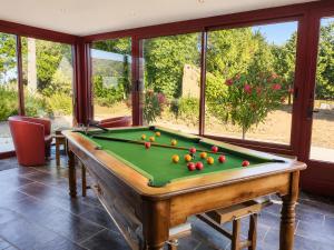 a pool table with balls on it in a room with windows at ti ar maez in Mauron