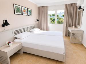 two beds in a white room with a window at Le Corail Apart'Hotel & Splash Park in Hammamet