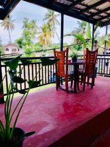 a table and chairs on a balcony with palm trees at S & B Villa Weligama in Weligama