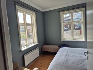 a bedroom with two windows and a bed at Steinhúsið in Hólmavík