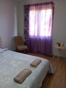 a bedroom with a bed and a window with a chair at Saulespuķe-Kuldīgā in Kuldīga