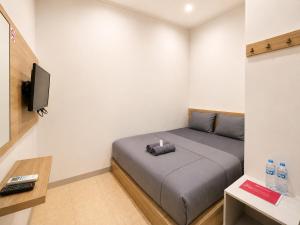 a small room with a bed and a tv at NamRoom at Jatiwaringin in Jakarta