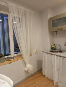 a white kitchen with a sink and a window at Saulespuķe-Kuldīgā in Kuldīga