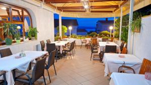 a restaurant with white tables and chairs on a patio at Pansion Klaudija in Crikvenica