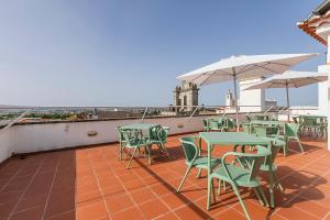 a patio with tables and chairs and umbrellas on a roof at HI Évora – Pousada de Juventude in Évora