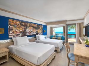 a hotel room with two beds and a view of the ocean at Novotel Phuket Resort in Patong Beach
