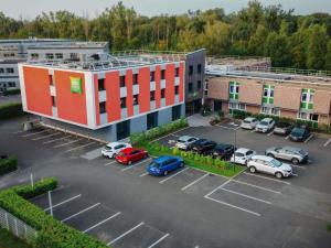 a building with cars parked in a parking lot at Ibis Styles Evry Lisses Paris Sud in Courcouronnes