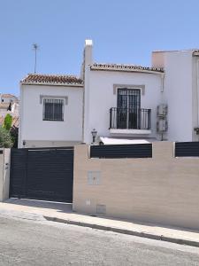 a white house with a black gate on a street at Casa Torrox Costa cerca del mar in Torrox