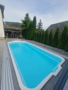 a large blue swimming pool in a yard at APARTAMENT POD ŚLIWKAMI in Krynica Zdrój