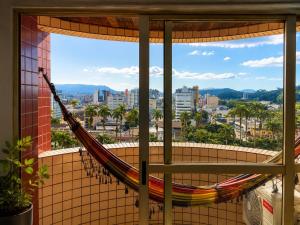 a hammock in a window with a view of a city at Apê completo bem no centro in Joinville