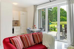 a living room with a red couch and a kitchen at Auszeit in der Heide mit Terrasse in Bienenbüttel