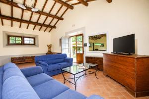 a living room with blue couches and a flat screen tv at Casale del Conte in Pienza