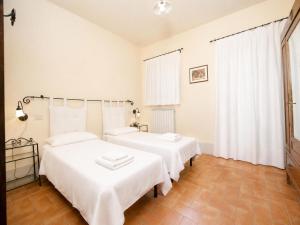 two beds in a bedroom with white sheets at Casale del Conte in Pienza +45 photos