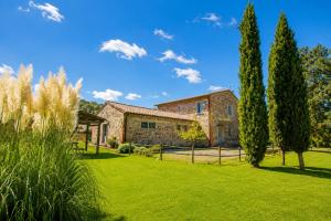 a stone house with trees in the yard at Casale del Conte in Pienza