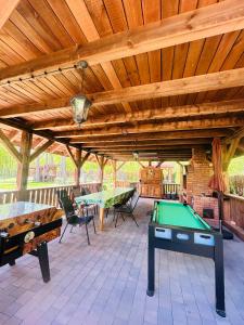a patio with ping pong tables and a wooden ceiling at Leśna Weranda pokoje gościnne FB Leśna Weranda in Ruciane-Nida