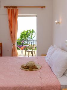 ein Zimmer mit einem Bett, einem Hut und einem Fenster in der Unterkunft Davis Studios & Apartments - Ήλια Βόρειας Εύβοιας - 1' από τη θάλασσα in Region Ilia