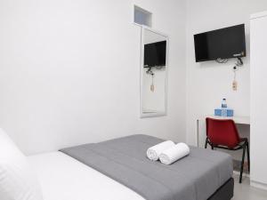 a white bedroom with a bed and a red chair at NamRoom at Jatiwaringin in Jakarta +32 photos