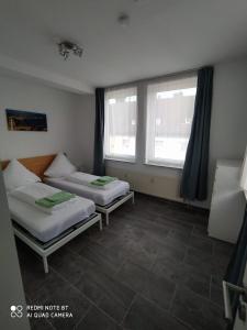 two beds in a room with two windows at Holidayapartment Bella Napoli in Liblar