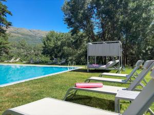 a pool with two lounge chairs next to a swimming pool at Hotel Rural Xerete in Navaconcejo