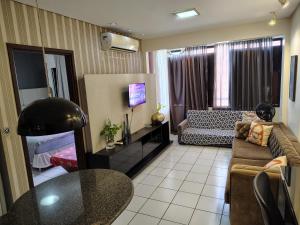 a living room with a couch a table and a television at Flat 203 Ed Clarice Lispector, Ilhotas- Rio Poty in Teresina