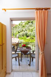Eine Glasschiebetür führt zu einem Balkon mit einem Tisch. in der Unterkunft Davis Studios & Apartments - Ήλια Βόρειας Εύβοιας - 1' από τη θάλασσα in Region Ilia