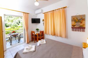 ein Zimmer mit einem Bett und einem Balkon mit einem Tisch in der Unterkunft Davis Studios & Apartments - Ήλια Βόρειας Εύβοιας - 1' από τη θάλασσα in Region Ilia