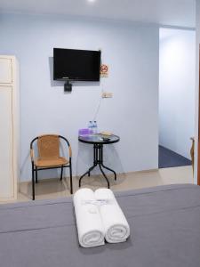 a room with a table and a tv and two towels at NamRoom at Jatiwaringin in Jakarta