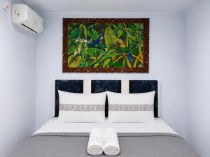 a bedroom with a bed with a painting on the wall at NamRoom at Jatiwaringin in Jakarta
