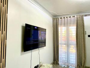 a flat screen tv on a wall in a room at Highway sunset in Namulanda