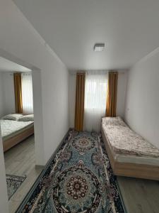 a bedroom with two beds and a rug at Guest House Nurdana in Tossor