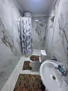 a white bathroom with a toilet and a sink at Guest House Nurdana in Tossor