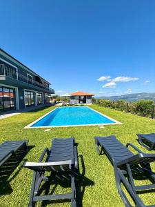 a swimming pool with lounge chairs and a house at Paraíso Céu Azul in Celorico de Basto