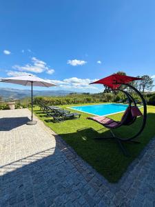 a resort with a pool and a chair and an umbrella at Paraíso Céu Azul in Celorico de Basto