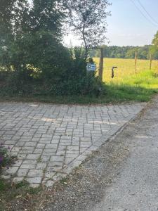a brick walkway next to a field with a sign at Escapade de charme à Questembert in Questembert