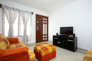 a living room with a couch and a television at La Casita Perfect Location in Cozumel