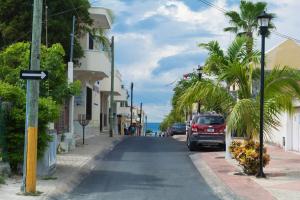 a street with palm trees and a car parked on the street at La Casita Perfect Location in Cozumel