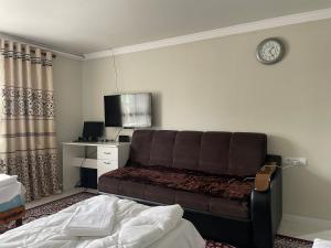 a hotel room with a couch and a clock on the wall at Kutbi Guest House in Bokonbayevo