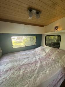a bed in the back of a camper with a window at La caravane du Farfadet in Flangebouche