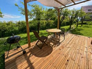 a grill and a table on a wooden deck at La caravane du Farfadet in Flangebouche