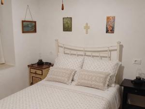 Ein weißes Bett mit zwei Kissen und einem Kreuz an der Wand in der Unterkunft Loggi House in Kástron